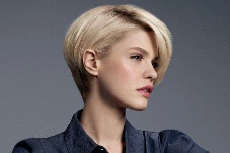 Žena s krátkým blond účesem typu pixie pro článek o dámských střizích.