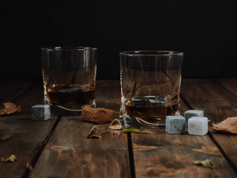 Dva sklenice s koňakem nebo whisky na dřevěném stole.