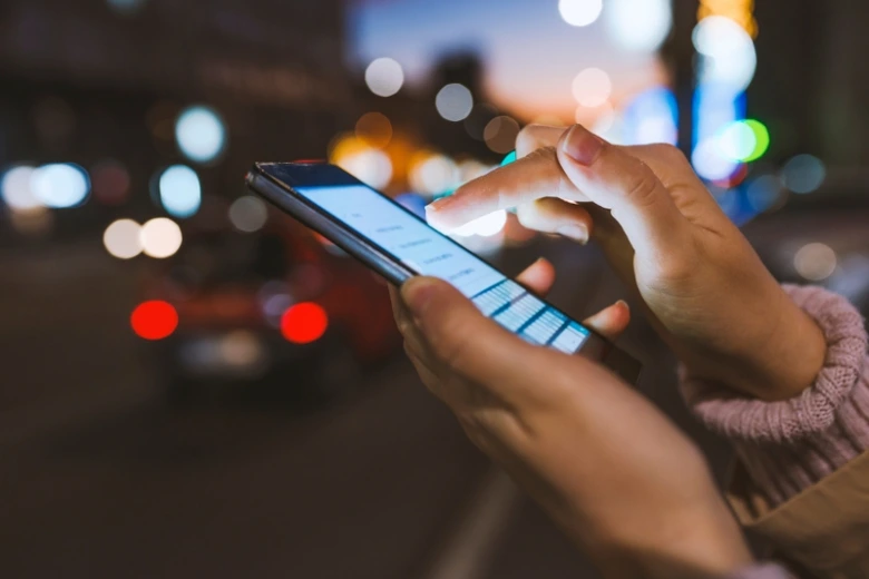 Ruce drží chytrý telefon v noci na ulici