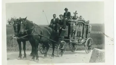 Historický pohřební vůz tažený koňmi s lidmi v šatech