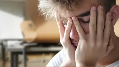 Uničený mladík v prázdné učebně symbolizující stres.