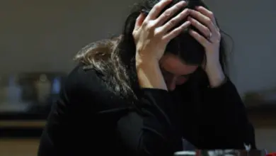 Žena v černém oděvu sedí a pláče po smrti manžela.