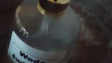 Skleněná lahvička s čerpacím mechanismem označená jako svatá voda.
