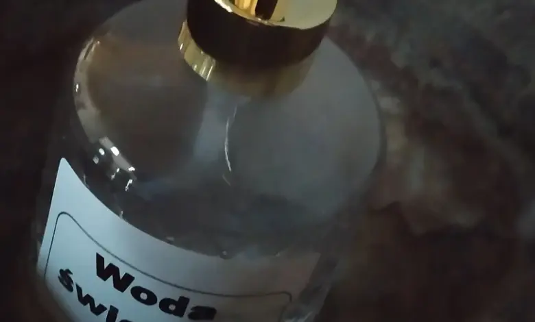 Skleněná lahvička s čerpacím mechanismem označená jako svatá voda.