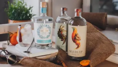 Tři lahve nealkoholických nápojů značky Seedlip na stole s ozdobami.