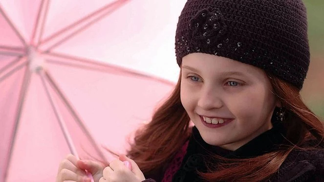 Usmívající se dívka s růžovou deštníkem.
