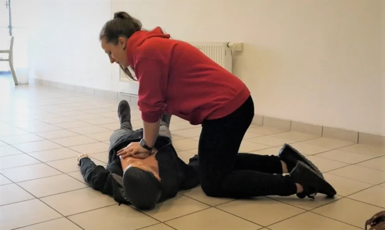 Žena provádí nepřímou srdeční masáž na tréninkovém modelu.