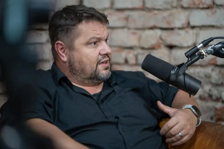 Muž mluví do mikrofonu v rozhovoru nebo podcastu.