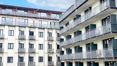 Moderní bytový dům s balkony v městské zástavbě.