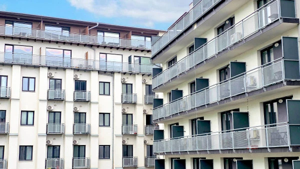 Moderní bytový dům s balkony v městské zástavbě.