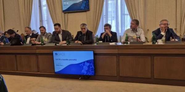 Skupina mužů na konferenci za dlouhým stolem.