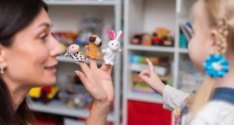 Žena s dítětem hraje na prstech zvířátka pro vývoj řeči.