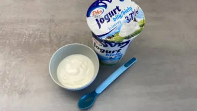 Bílý jogurt v misce s modlou lžičkou pro děti.