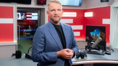 Muž v televizní studiu s mikrofony a monitory