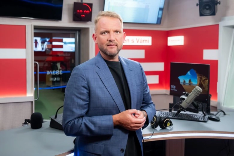 Muž v televizní studiu s mikrofony a monitory