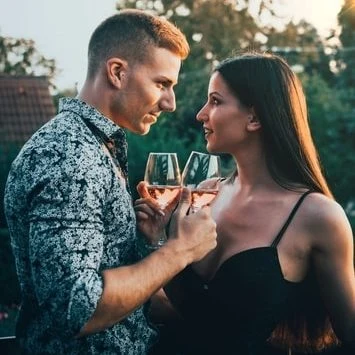 Muž a žena se usmívají na sebe při zdvižení sklenic vína.