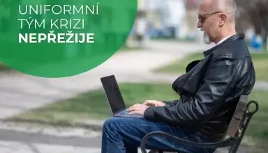 Muž sedí na lavičce s notebookem v parku.