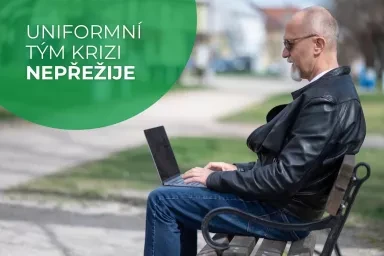 Muž sedí na lavičce s notebookem v parku.