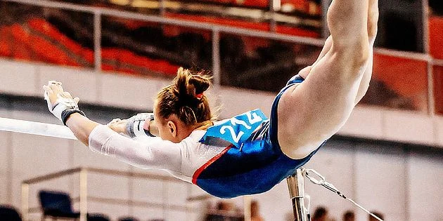 Ženská gymnastka na lavičkách během soutěže.