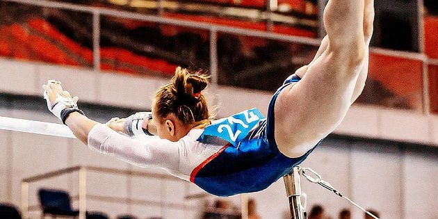 Žena gymnastka na lavičkách v soutěži.