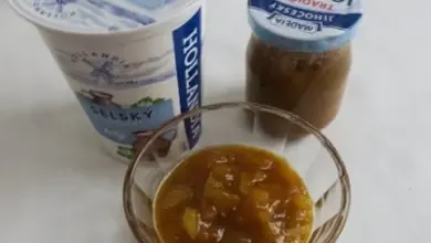 Skleněná miska s ovocným kompotem vedle jogurtu.