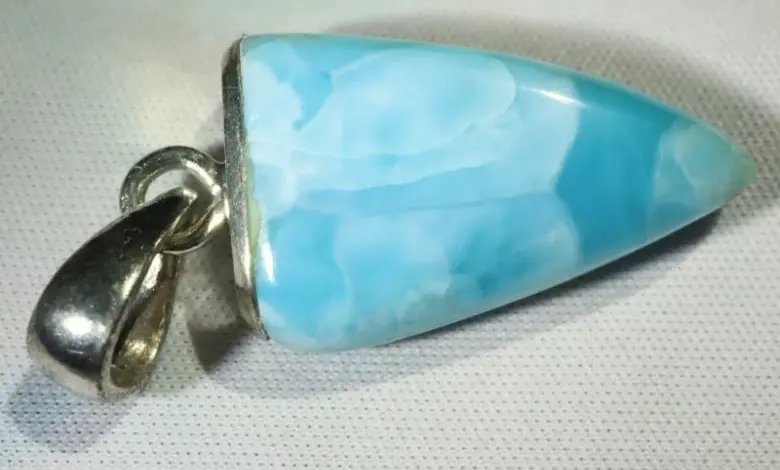 Modrý kámen larimar v stříbrném náhrdelníku na bílém pozadí.
