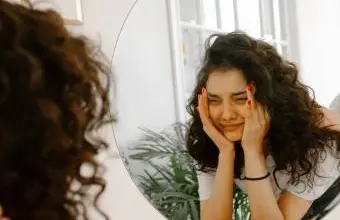 Dívka se dívá do zrcadla s výrazem smutku.