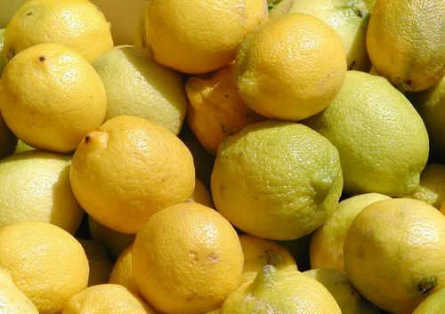 Hromada čerstvých žlutých citronů na světlém pozadí.