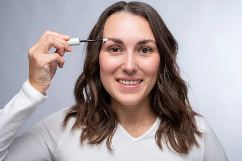 Žena aplikuje gel na obočí po permanentním make-upu.
