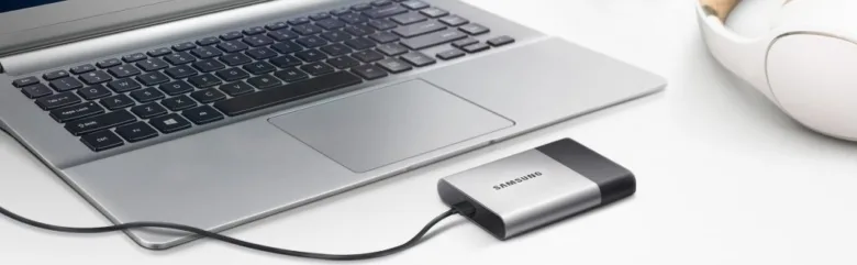 Samsung externí disk připojený k notebooku na bílém stole.