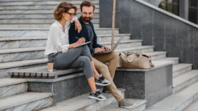 Muž a žena v neformálním oblečení pracují venku na schodech.