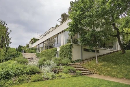 Moderní dům na svahu s okny v architektonickém stylu.