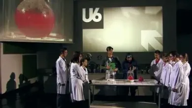 Skupina lidí v laboratorních pláštích s chemickým vybavením.