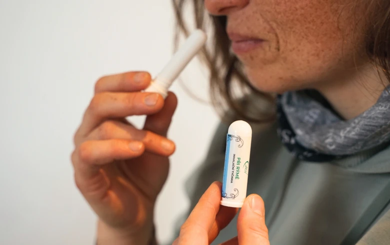 Žena drží inhalátor s éterickými oleji u nosu pro inhalační použití.