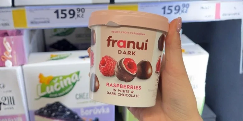 Ruce drží čokoládovou nádobu s malinami v bílé i tmavé čokoládě.