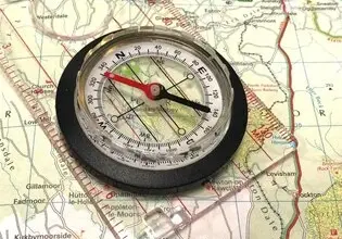 Kompas položený na turistické mapě pro orientaci v terénu.