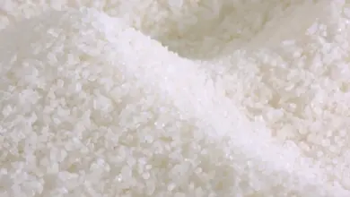 Blízký záběr na bílý granulovaný cukr s viditelnou strukturou krystalů.