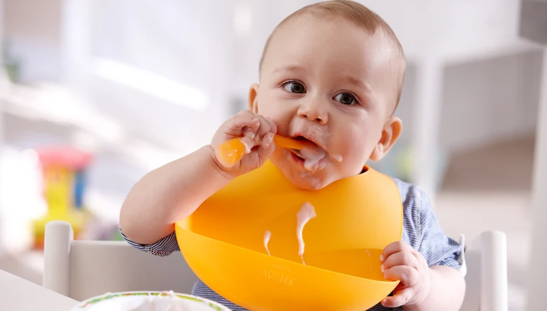 Mimořádně šťastné dítě sedící v židli s oranžovou kapesníkem.