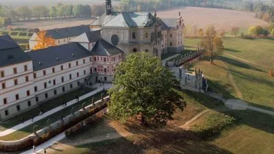 Historický klášter s barokní architekturou v podzimním krajině.